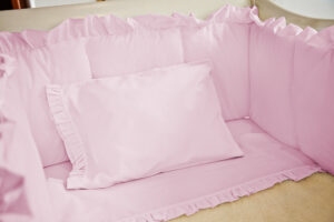 Juego de sábanas rosado con boleros para cuna
